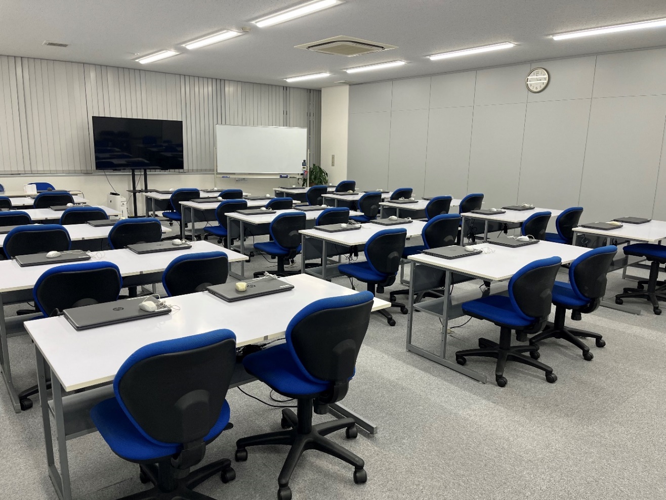 新栄ビル5階503号室の教室。机にパソコンが並び、青い椅子が配置されている